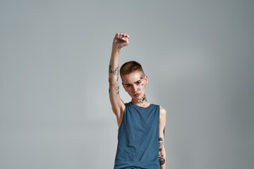 Tattooed young caucasian woman protester with piercing looking at camera while posing with raised...