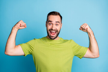 Photo of excited crazy strong man show raise hands biceps cheerful mood isolated on pastel blue color background