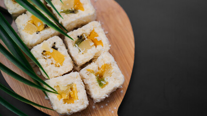 Dessert sushi. Sweet kiwi, pineapple and banana sushi rolls. Sushi on a wooden tray on a black background