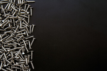 Closeup of steel screws one black background with copy space