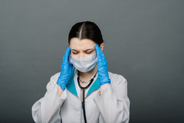 Beautiful female doctor in mask looking away and thinking about something.