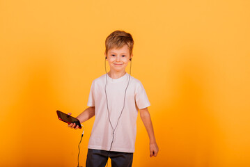 Emotions boy listens to music with headphones on his phone, yellow background. Children's fairy tales in headphones.