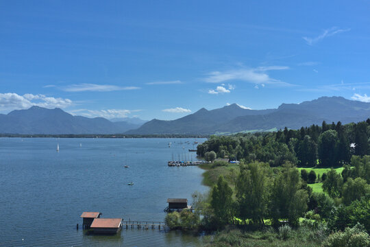 View over the lake Chiemsee in Bavaria towards the Bavarian Alps with a blue sky and some white clouds