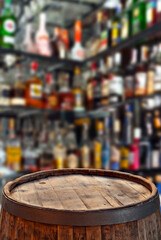 Wooden board on a background of bottles with alcohol. Old bar counter as layout for design. Workpiece for design. Empty place to advertise products. Blurred interior of the bar in the background.