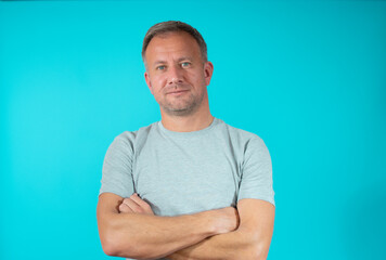 Handsome young man smiling with arms crossed over green background