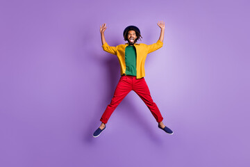 Fototapeta na wymiar Full length photo of cheerful dark skin guy dressed yellow shirt jumping high rising arms hands isolated purple color background