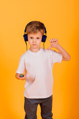 Emotions boy listens to music with headphones on his phone, yellow background. Children's fairy...