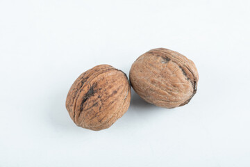 Two whole healthy walnuts on a white background