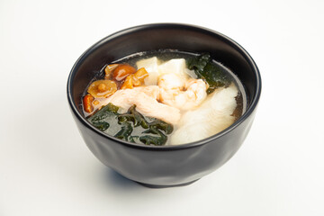 Miso soup with seafood in a black karelka. Ingredients broth, shrimp, salmon, perch, Tofu cheese, nameko mushrooms, miso paste, hondashi, wakame. For restaurant menu