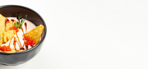 Creamy salmon soup in a black carriage. Ingredients cream, salmon, vegetable oil, salmon caviar, Teriyaki sauce, Nachos chips, salt. For restaurant menu