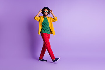 Full length profile photo of carefree dark skin man arms touch cap toothy smile isolated on violet...