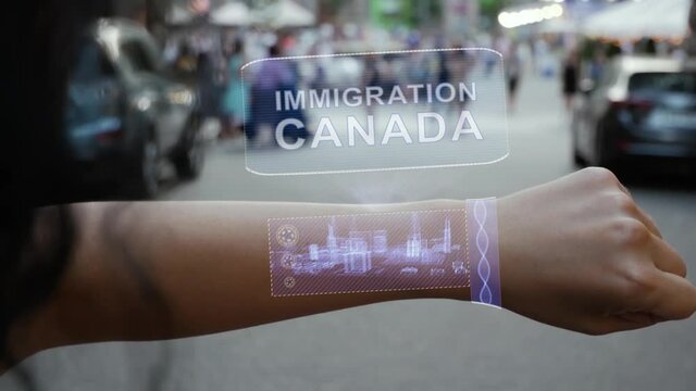 Female hand activates conceptual HUD holograms on smart bracelet with text Immigration Canada. Unrecognizable woman with holographic technology on a city street background