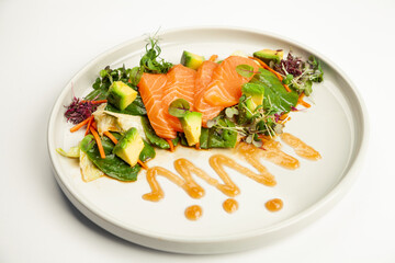 Salmon and avocado salad in tamarind sauce on a plate. Ingredients Iceberg lettuce, salmon, avocado, spinach, carrot, tamarind sauce. For restaurant menu