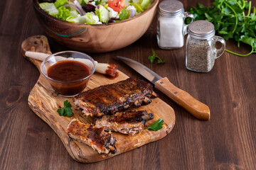 A rack of spareribs covered in barbecue sauce on a wooden board.