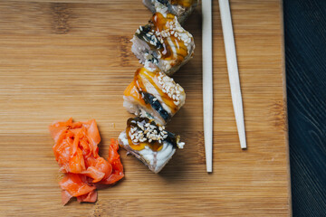 sushi rolls chopsticks ginger red on wooden board