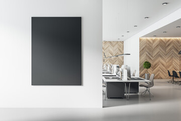 Blank black poster on white wall in modern sunny open space office with wooden wall. Mockup