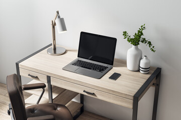 Blank black laptop display on wooden table with modern lamp, vase and leather chair on the floor. Home office concept. Mockup