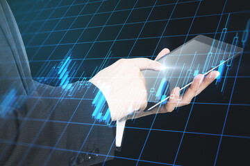 Online investment concept with businessman hand using digital tablet and digital display with glowing financial graphs