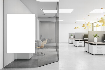 Blank white poster on glass wall in modern open space office with grey furniture and yellow lights....