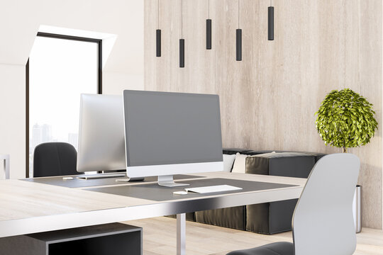Cozy workplace with modern computer monitor with blank grey screen and minimalistic style furniture in sunny office with woodem wall