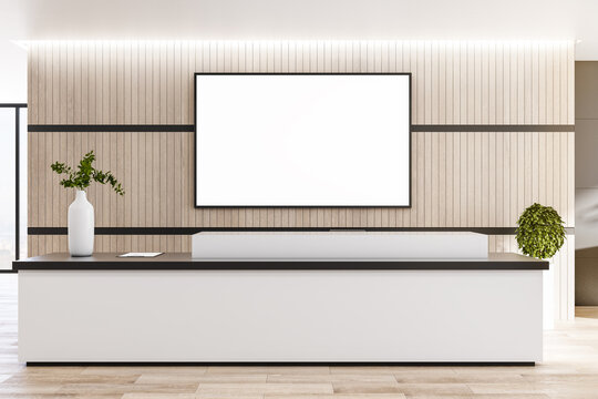 Blank white screen in black frame on wooden wall behind reception area in modern eco style office. Mockup