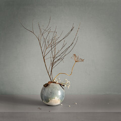 Composition with dried plants in a round ceramic vase.