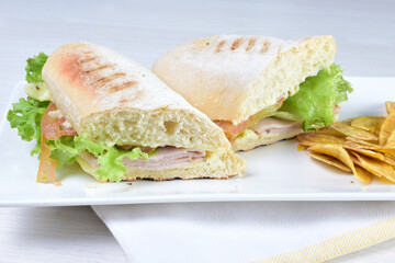 Ham, cheese and lettuce sandwich on white wooden background