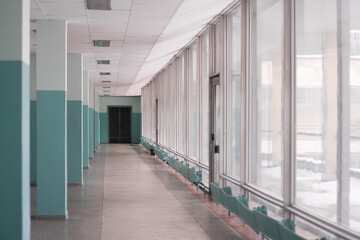 Long bright empty corridor with wide windows of the old building in the style of Soviet modernism, in the afternoon.