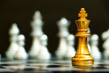Gold king in chess game face with the another silver team on black background (Concept for company...