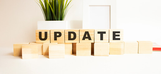 Wooden cubes with letters on a white table. The word is UPDATE . White background.