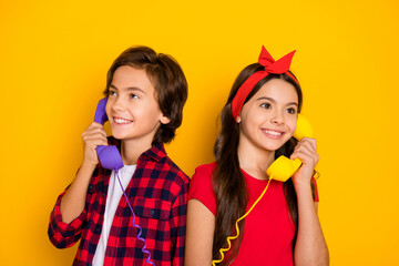 Portrait of cheerful kids hand hold vintage handset receive call speak isolated on yellow color...