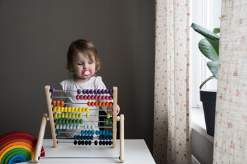 a little girl is playing educational games. a child counts on colorful wooden abacus. home games with children