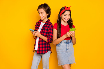 Photo of two children hold telephone look screen wear red casual clothes isolated yellow color background