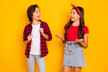 Portrait of positive boy girl look each other speak explain toothy smile isolated on yellow color background - Powered by Adobe