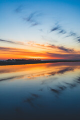 波の水たまりに反射した夕日と空と雲