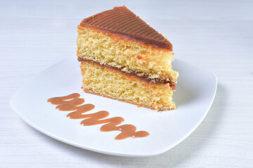 Cake decorated with vanilla and arequipe on white plate and light colored wooden background