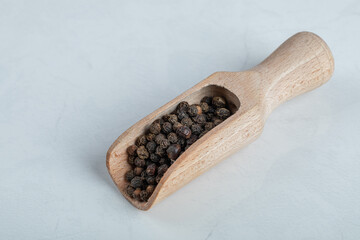 A wooden spoon full of dried peppercorns