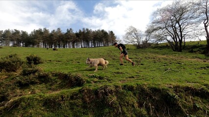 young man trail running in the mointains with his dog