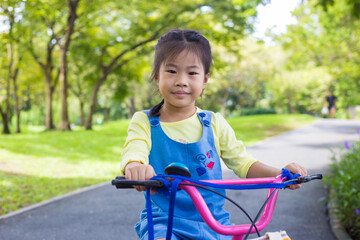 Obraz premium Little girl with bike in city public park nature recreation