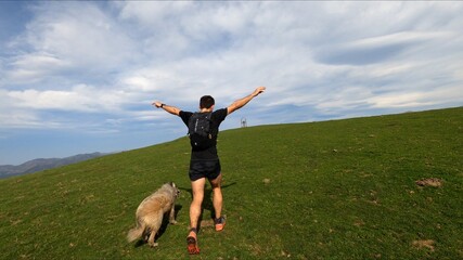 young man trail running in the mointains with his dog
