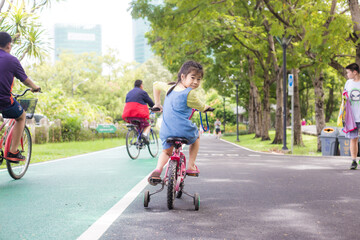 Fototapeta premium Little girl with bike in city public park nature recreation
