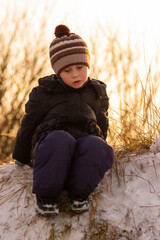 Little boy playing on a snow slide. The concept of active recreation of children in nature. Winter walks