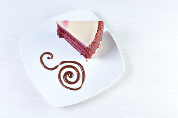Red velvet cake decorated cake on white plate and light colored wooden background