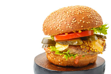 Classic burger with beef, cheese vegetables in sauce with French mustard on a bun with sesame seeds on a wooden round stand on a white background isolate.