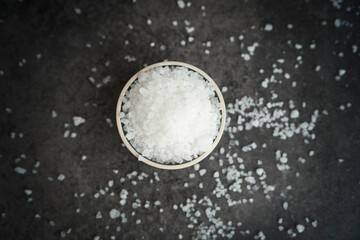 Top view of salt grains in bowl over a dark background