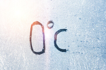 32 degrees Fahrenheit or 0 Celsius number lettering on icy glass covered with ice and frost. The concept of extreme cold weather.