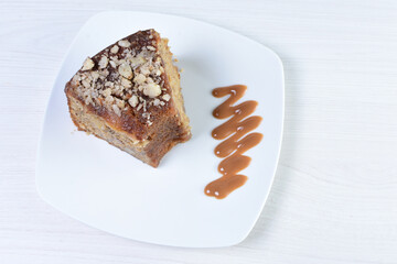 Cake decorated with vanilla and arequipe on white plate and light colored wooden background