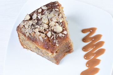 Cake decorated with vanilla and arequipe on white plate and light colored wooden background