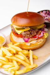 Photo of tasty delicious burger with fry potatoes and sauce over white background, fast food.