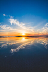 波の水たまりに反射した夕日と空と雲